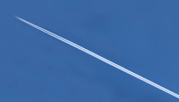 trilha branca de um avião enquanto voa no céu azul
 - Foto, Imagem