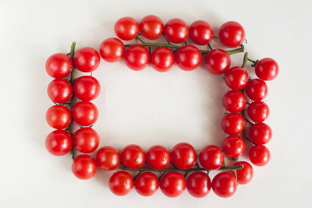 Cuatro ramitas de tomates cherry en forma de marco sobre un fondo claro. La vista desde arriba. Espacio para texto
 - Foto, Imagen