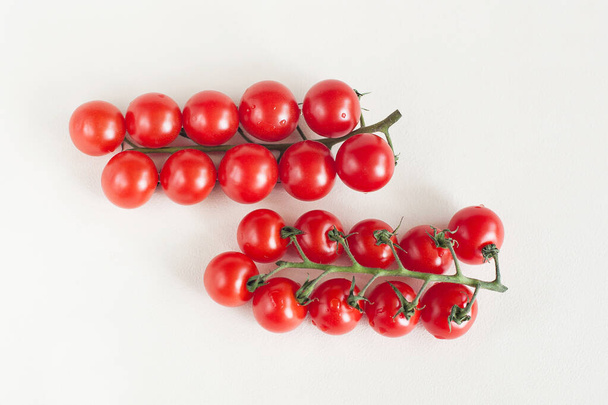 Açık bir arkaplanda paralel duran iki tutam kiraz domatesi. - Fotoğraf, Görsel