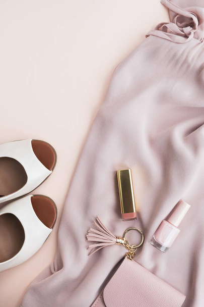 Womens fashion accessories on beige pastel background. Dress, high heel shoes, purse and cosmetics. Fashion blog, shopping, sale concept. Top view, flat lay, vertical - Photo, Image