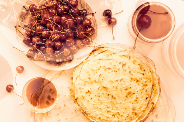 Blurry background, double exposure, homemade pancakes, crepes, fruit juice and fresh cherry berries - Φωτογραφία, εικόνα