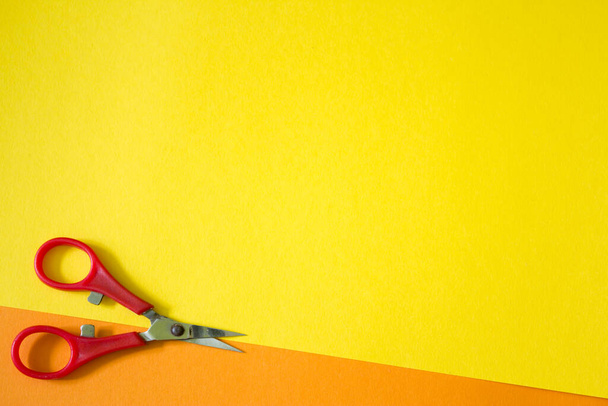 red scissors on orange and yellow background - Foto, Bild