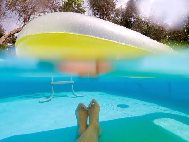 Split Underwater Pov di un uomo che si rilassa in piscina sotto un materasso ad aria galleggiante - Foto, immagini