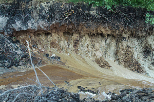 Kaivettu reikä maahan on täynnä vettä tasolle. Suo elementistä, joka tuhosi ihmisen toiminnan. Osakkeen abstrakti tausta - Valokuva, kuva