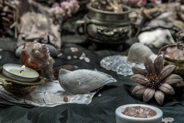 Beauty composition with Burning candle aroma oil lamp and Dry flower petals and Pine cones, Natural pine wood disc, Stones and Shells, Himalayan salt on dark background. Aromatherapy concept. - Foto, Imagem