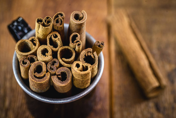 Cinnamon sticks isolated on background rustic wood inside black mug. - Valokuva, kuva