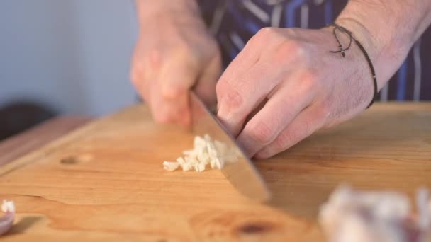 Slow motion of chef's hands slicing garlic during food preparation in the kitchen - Footage, Video