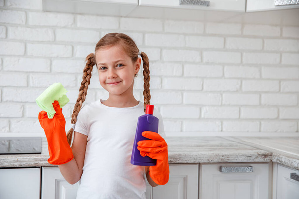 Girl child in kitchen holds products for cleaning house - Foto, Imagen