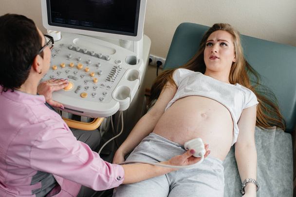 A pregnant girl gets an ultrasound of her abdomen at the clinic. Medical examination - Photo, image