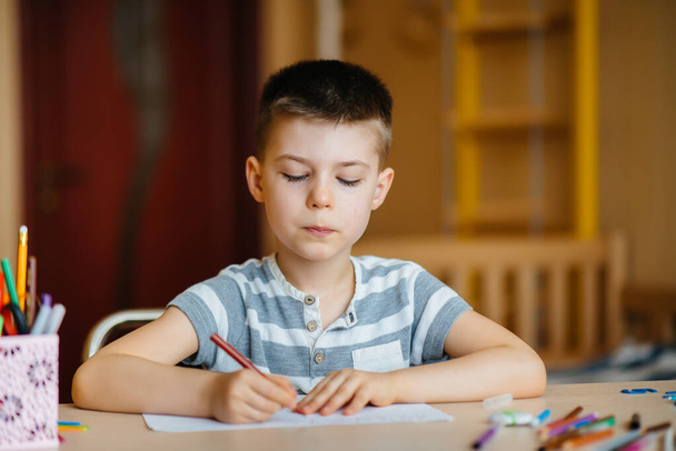 A school-age boy does homework at home. Training at school - 写真・画像