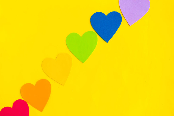 Hearts in lgbtq colors on bright yellow background, top view - Zdjęcie, obraz
