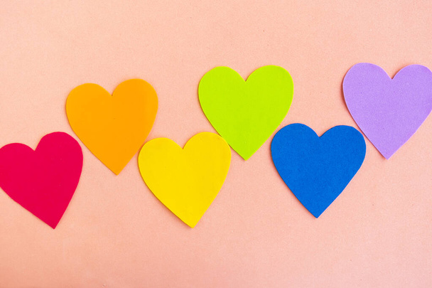 Hearts in lgbtq colors on pastel pink background, top view - Fotó, kép