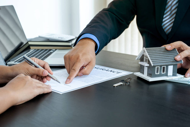 Kupujący podpisuje umowę najmu, zakupu hipoteki lub ubezpieczenia domu przed agentem nieruchomości. - Zdjęcie, obraz