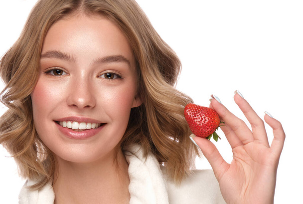 Beautiful tender young girl in a white coat with clean fresh skin posing in front of the camera with strawberries in her hands. Beauty face. Skin care. - Fotoğraf, Görsel