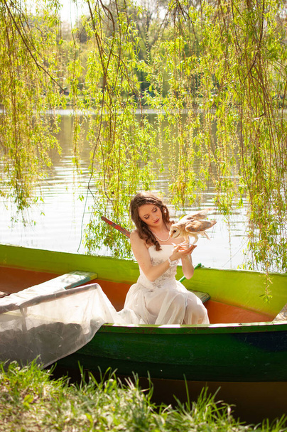 Magisch portret van mooie bruid in witte trouwjurk met echte schuur uil op boot - Foto, afbeelding