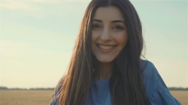 Portret van goed uitziende blanke jonge vrouw die voor de camera staat en glimlacht - Video