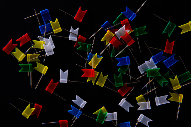 pines de mapa de marcadores en forma de bandera de papelería multicolor sobre fondo negro, vista cercana
   - Foto, imagen