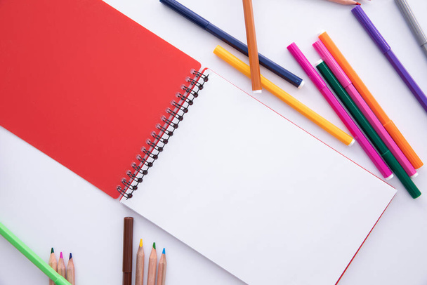 коллекция цветных фломастерных ручек с карандашами и ноутбуком на светлом фоне, близкий обзор
  - Фото, изображение