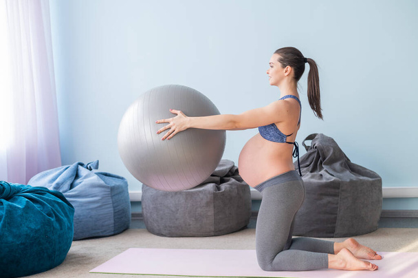 Pregnant caucasian woman on fitness with a ball. Yoga for expectant mothers. Girl in the classroom in preparation for childbirth. Pilates in the last trimester. - Foto, Imagem