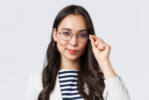 Negócios, finanças e emprego, conceito de empresárias bem sucedidas. Close-up de confiante jovem asiático empresária fixando óculos e olhando determinado, pronto para assinar acordo
 - Foto, Imagem