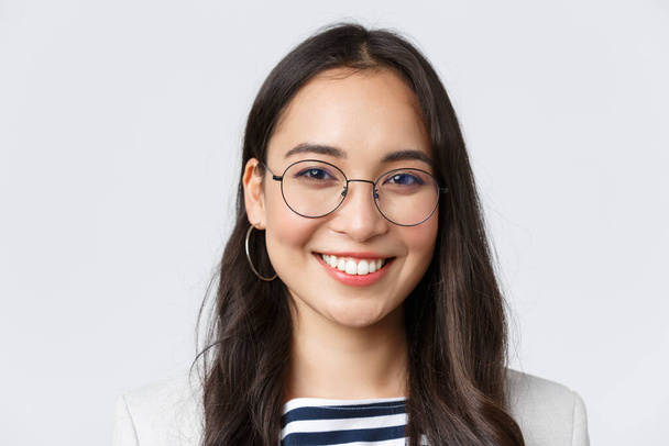 Unternehmen, Finanzen und Beschäftigung, erfolgreiche Unternehmerinnen. Gut aussehende asiatische Geschäftsfrau in Brille und Anzug lächelt freundlich und selbstbewusst, arbeitet im Büro - Foto, Bild