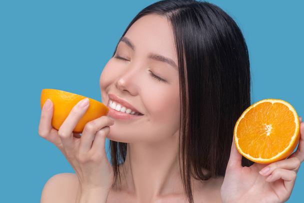 Young woman tasting a fresh juicy orange - Fotoğraf, Görsel