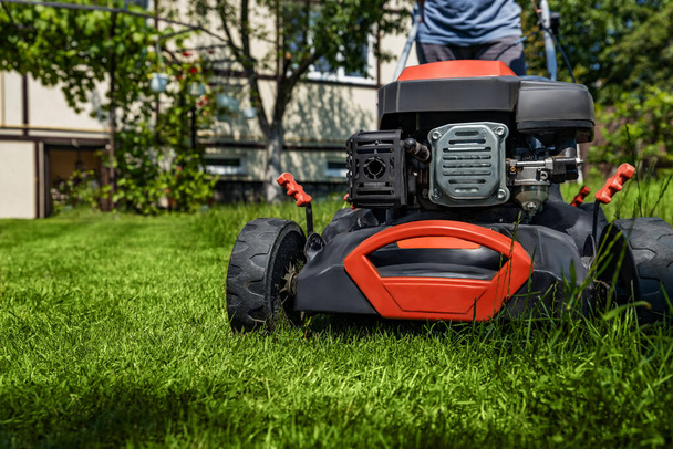 A man moves with a lawn mower and mows green grass. Garden care concept - Photo, image