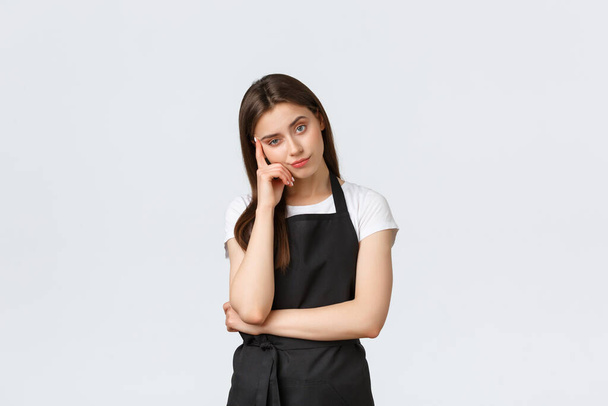 Grocery store employees, small business and coffee shops concept. Annoyed tired saleswoman fed up listening to boring story. Female barista staring bothered at camera, white background - Photo, Image