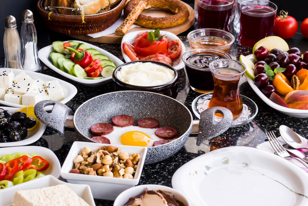 Desayuno turco tradicional con sartén de huevo de salchicha en la mesa de mármol de granito.Vista cercana y grande              - Foto, imagen