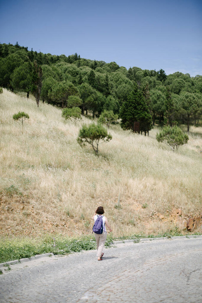 Sırt çantası tatili. Sırt çantalı bir kadın yolda tek başına yürüyor.. - Fotoğraf, Görsel