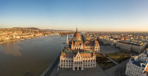 Drone aérien panoramique de la façade sud du Parlement hongrois pendant le lever du soleil à Budapest en hiver - Photo, image