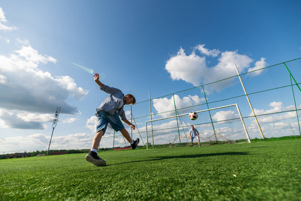 Boy kicking a penalty at goal. Low angle wide view. - Photo, image
