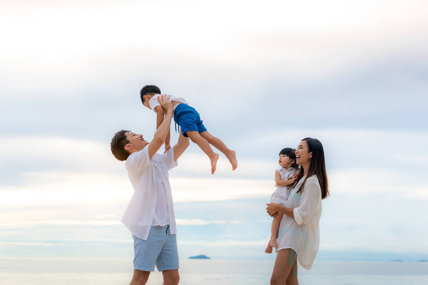 Mutlu Asyalı aile tatilleri. Mutlu baba, anne, oğul ve kız tatilleri. Yaz günbatımı denizi boyunca gökyüzüne doğru yürüyorlar. Tatilde, yazda ve tatilde mutlu aile seyahatleri. - Fotoğraf, Görsel