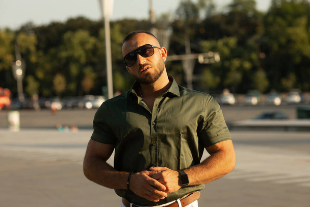 Attractive young bearded male model posing outdoors in shirt and sunglasses. - Fotografie, Obrázek