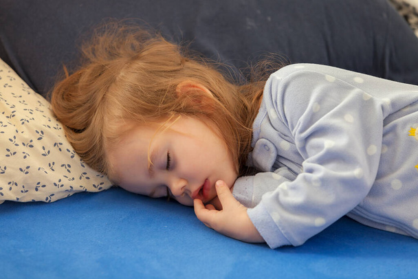 Bambina che dorme sul letto con lenzuola blu, nota profondità di campo poco profonda - Foto, immagini