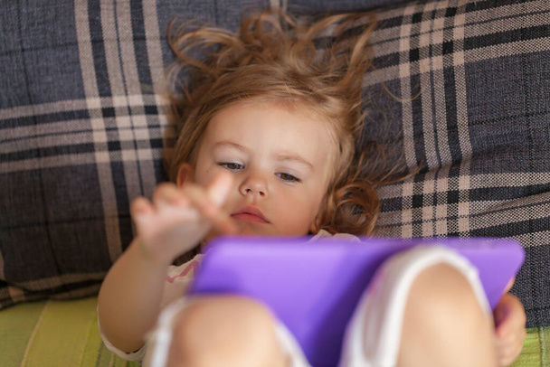 little girl lying in bed and looking cartoon on the laptop, note shallow depth of field - 写真・画像
