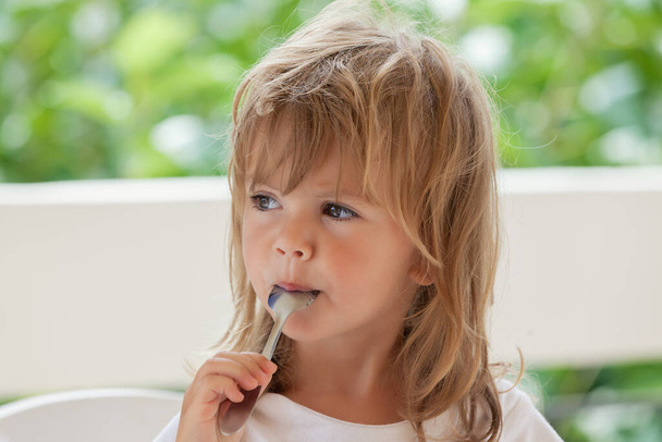 little girl eats honey with a spoon - Foto, Imagem