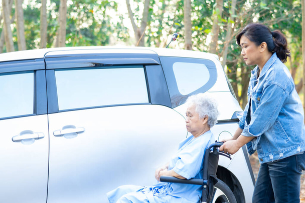 Aide et soutien asiatique personne âgée ou âgée vieille dame patiente assise sur fauteuil roulant se préparer obtenir à sa voiture, concept médical fort sain. - Photo, image