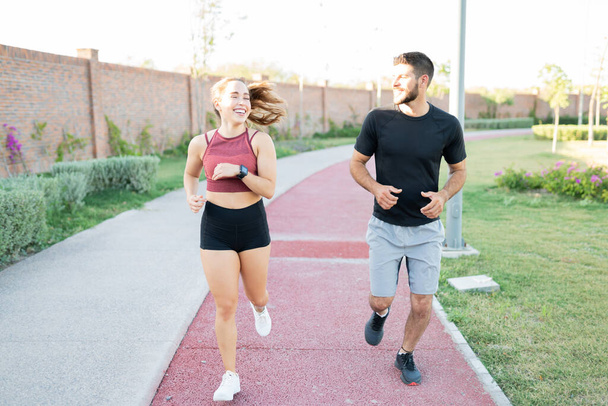 Piena lunghezza di sorridente atletica coppia jogging nel parco - Foto, immagini
