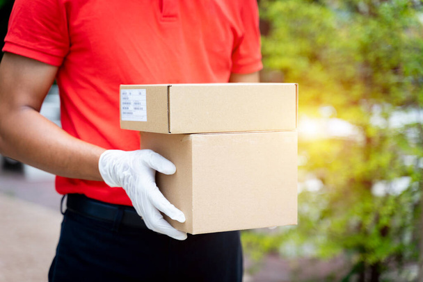 Großaufnahme eines Zustellers hält Pakete und Kartons vor dem Haus des Kunden, um während der COVID-19-Pandemie online einzukaufen. Zusteller liefert Paketpost aus. - Foto, Bild