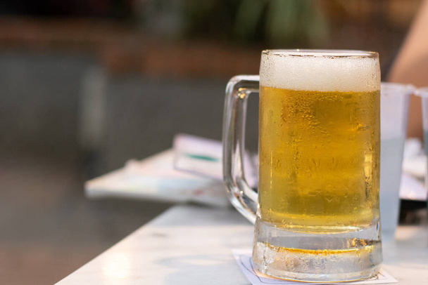 Close up da cerveja de vidro frio com espuma no pub & restaurante de fundo
. - Foto, Imagem