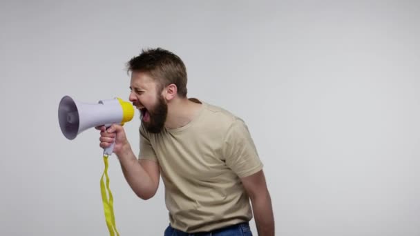 Attention, advertisement! Bearded man talking with megaphone, loudly announcing news or warning, using loudspeaker for idea proclamation, shouting speech. studio shot isolated on gray background - Imágenes, Vídeo