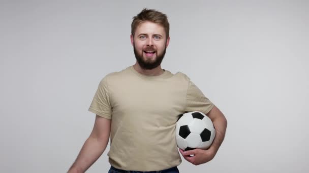 Joyful happy football fan bearded guy in t-shirt holding soccer ball and waving European Union flag, excited about winning goal, cheering for favorite sport game. studio shot isolated, gray background - Video