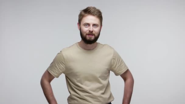 Love you! Handsome bearded guy in t-shirt sending air kisses over palms, looking at camera demonstrating affection feelings, romance in relations. indoor studio shot isolated on gray background - Footage, Video
