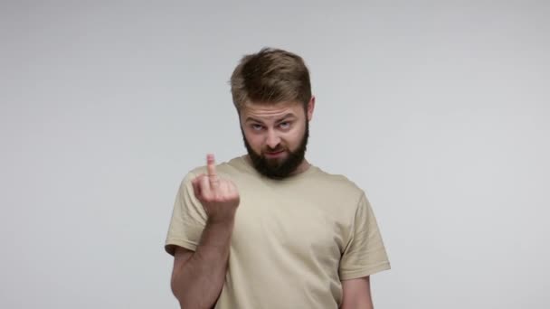 Crazy hooligan bearded man showing around his middle fingers, demonstrating protest with impolite rude gesture of disrespect, rejecting communication. indoor studio shot isolated on gray background - 映像、動画