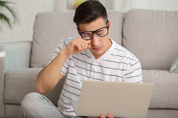Young man suffering from sleep deprivation with laptop at home - Φωτογραφία, εικόνα