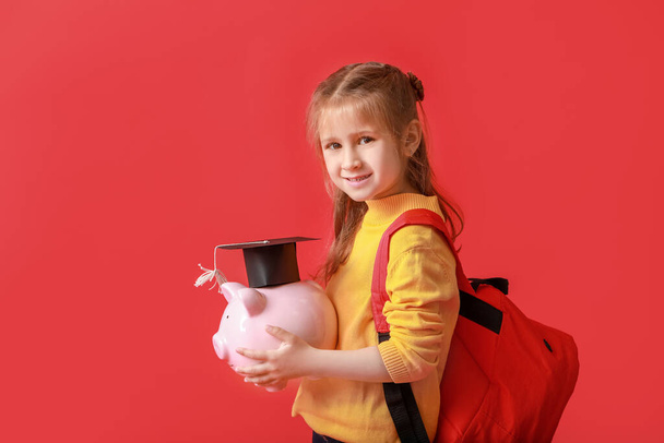 Little girl with savings for education on color background - Photo, Image