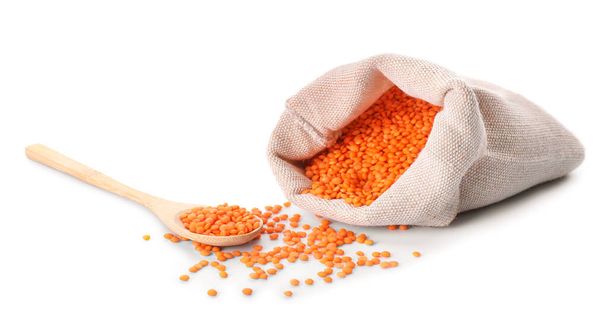 Borsa e cucchiaio con lenticchie rosse su sfondo bianco - Foto, immagini