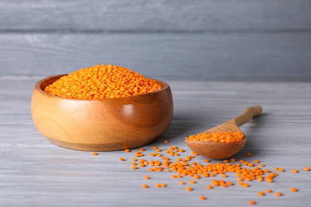 Bowl and spoon with red lentils on wooden background - Zdjęcie, obraz