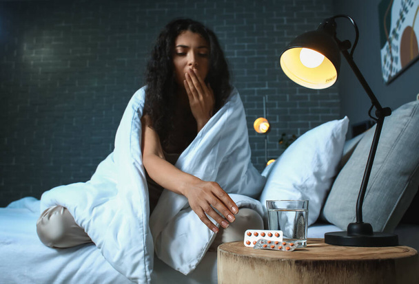 Kobieta zażywająca tabletki nasenne w nocy - Zdjęcie, obraz